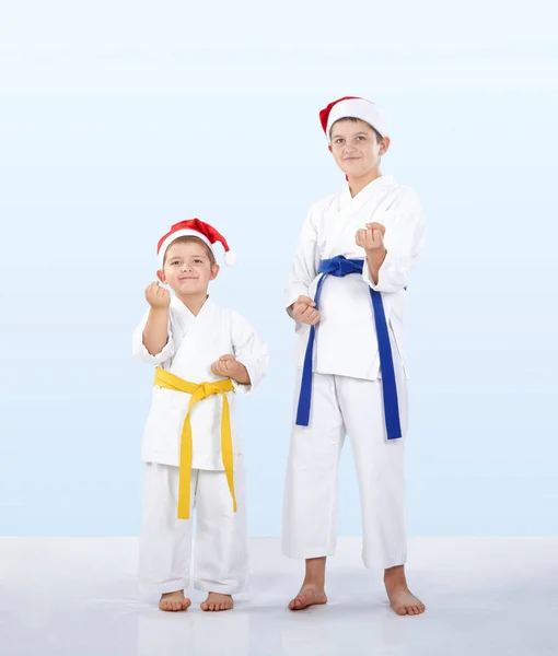 In the caps of Santa Claus sportsmen stand in the rack of karate — Stock Photo, Image