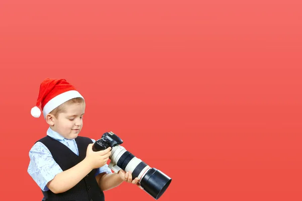 Em um pequeno fotógrafo de fundo vermelho em boné de Papai Noel — Fotografia de Stock