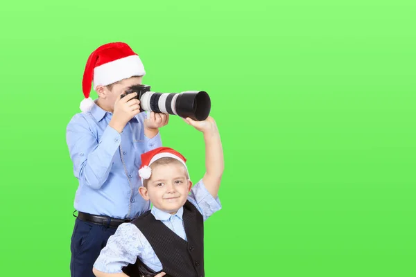 Irmãozinho ajudando o irmão está fotografando em um fundo verde — Fotografia de Stock