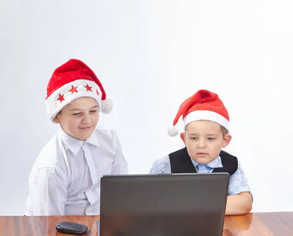 Les enfants regardent un ordinateur portable dans les casquettes du Père Noël — Photo
