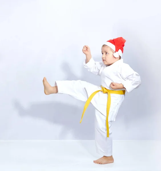 Chłopak w czapce Mikołaja jest trening kick nogi — Zdjęcie stockowe