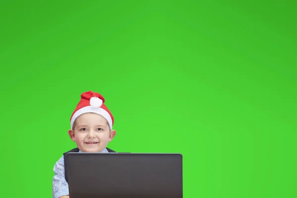 Un enfant portant une casquette du Père Noël regardant un ordinateur portable — Photo