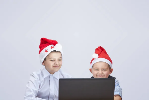 Auf grauem Hintergrund schauen die Jungen auf einen Laptop — Stockfoto