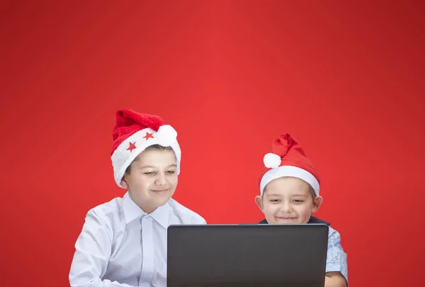 Brüder in Weihnachtsmannmützen schauen auf einen Laptop — Stockfoto