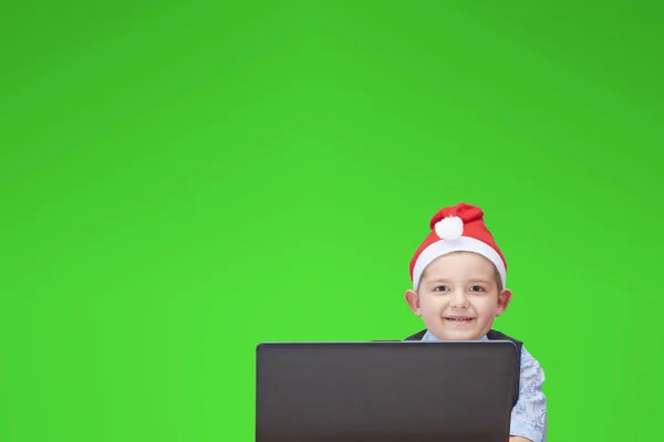 Fröhlicher Junge blickt auf einen Laptop auf grünem Hintergrund — Stockfoto