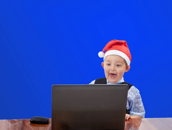 Das Kind blickt auf einen Laptop auf blauem Hintergrund — Stockfoto
