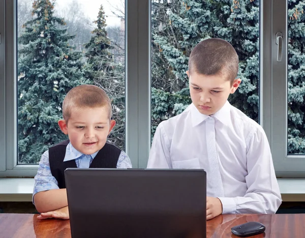 Vor dem Hintergrund eines Fensters mit Weihnachtsbäumen schauen die Jungen auf den Monitor — Stockfoto