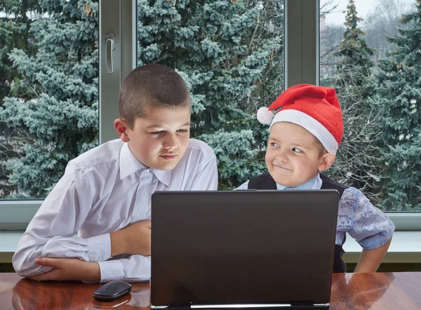 En casquette du Père Noël, les frères regardent l'ordinateur portable — Photo