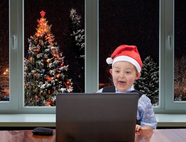 Noel Baba çocuğun pencerenin dışındaki Noel ağacı arka plan üzerinde bir laptop arıyorum kap içinde