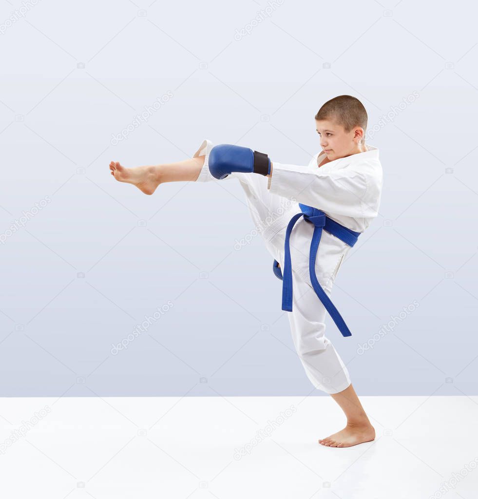 Boy with blue belt and overlays on the hands is beating kicking