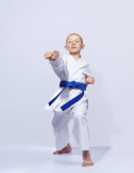 Karateka-Junge schlägt Schlagarm vor hellem Hintergrund — Stockfoto