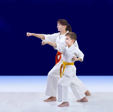 Sporcular anne ve oğlu eğitim koyu mavi bir arka plan üzerinde kol yumruk