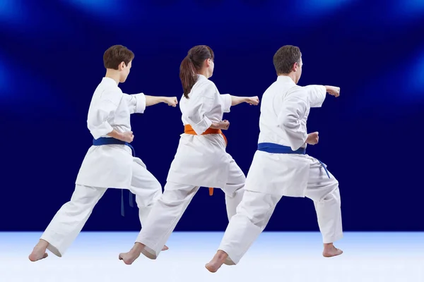 Blows arm adult friends athletes are training on the dark blue background — Stock Photo, Image