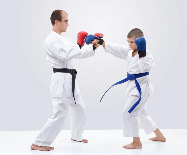 Karateka boy is training blows on overlays trainer — Stock Photo, Image