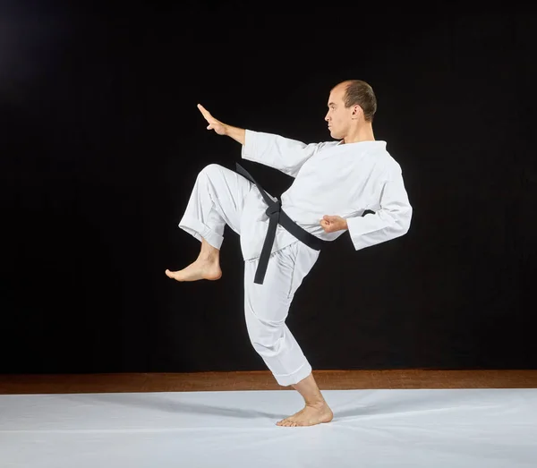 Egy férfi karategi veri a rúgás láb egy fekete háttér — Stock Fotó