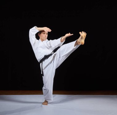 Sporcu karate darbeler siyah bir arka plan karşı trenler 