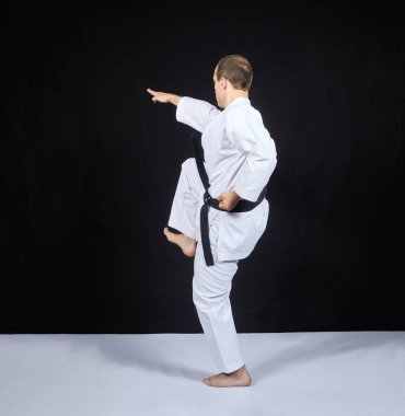 Siyah bir arka plan üzerine bir karate sporcu bir diz ile yener.