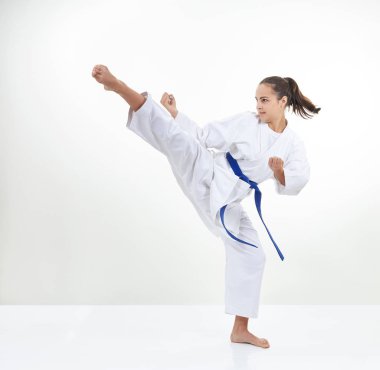 An adult sportswoman in karategi beats kick clipart