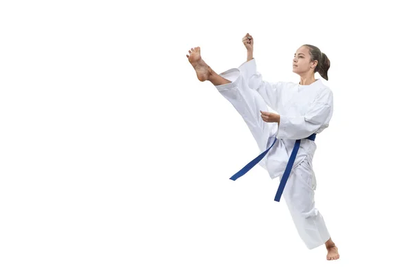 På en vit bakgrund slår flickan med ett blått bälte kick — Stockfoto