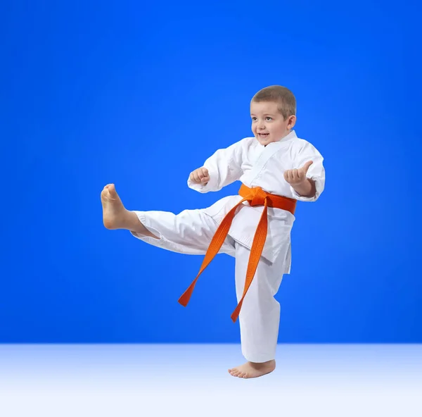 The boy with an orange belt is beating kick leg — Stock Photo, Image