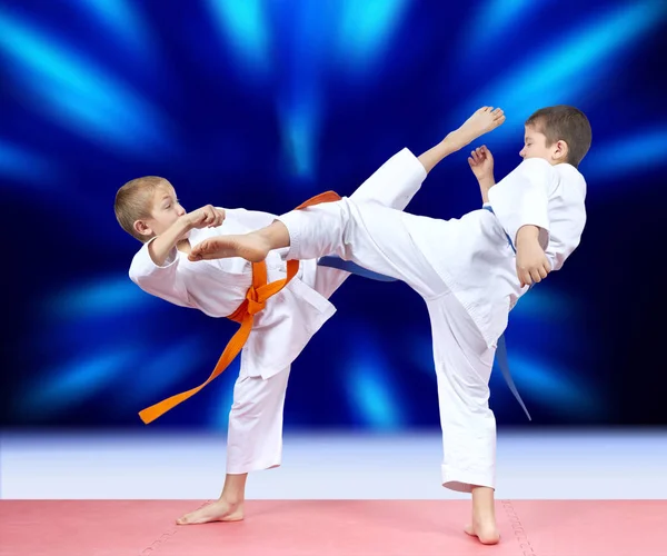 Enfants athlètes battent coups de pied sur un fond bleu vif — Photo