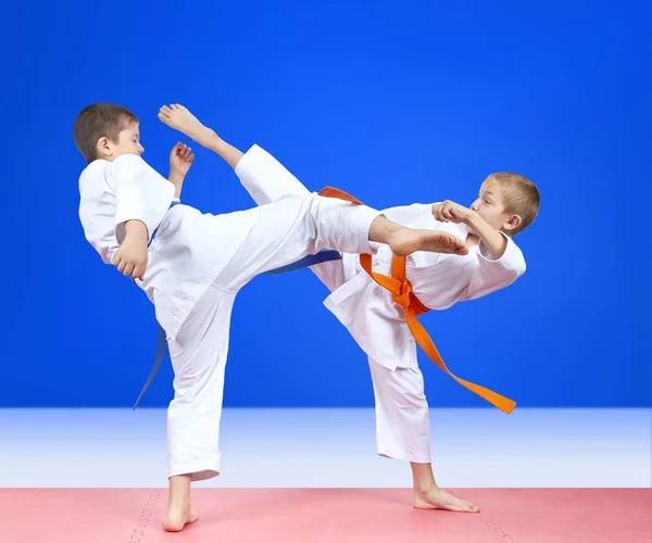 На синем фоне два спортсмена тренируют ногами — стоковое фото