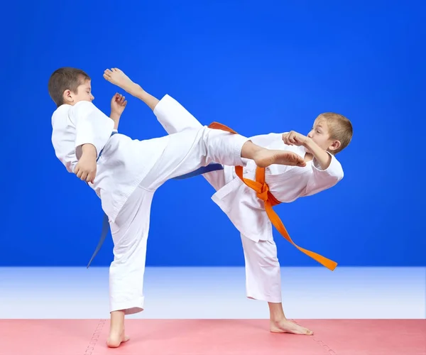 Auf blauem Hintergrund trainieren zwei Athleten das Kickbein — Stockfoto