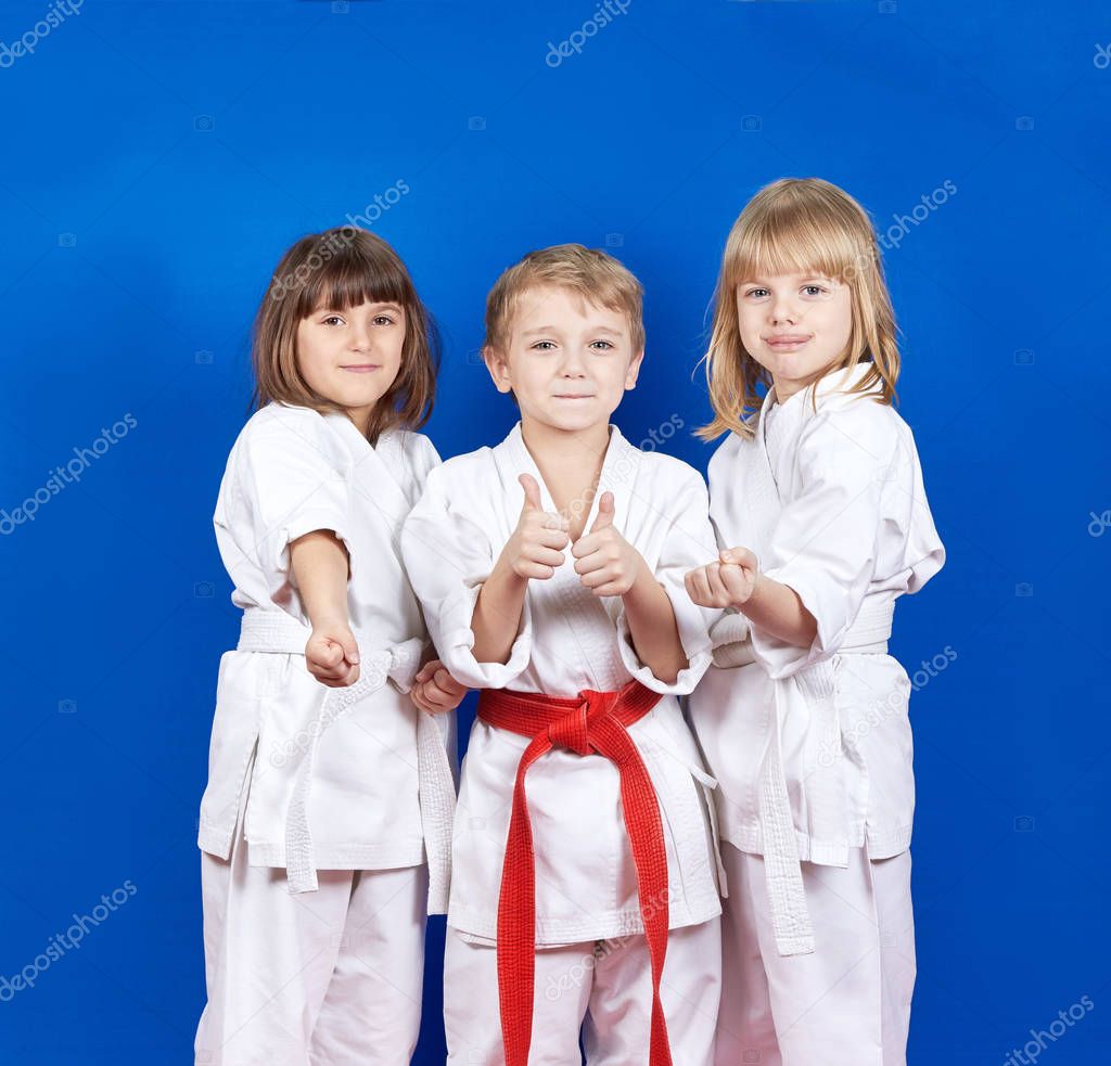 Three children standing in karate rack and showing finger super