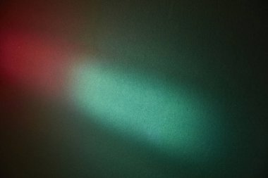 Koyu yeşil arkaplanda kırmızı parıltılı turkuaz ışık lekesi