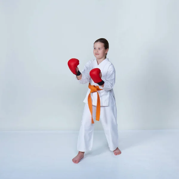 On a light background with an orange belt athlete stands in rack of a karate