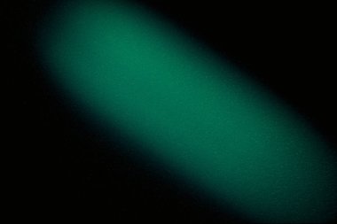 Koyu yeşil dokular, siyah arkaplanda geniş çapraz ışık demeti bulanıklaştırdı.