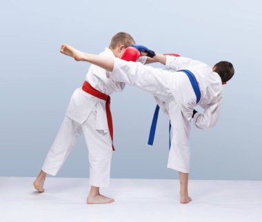 Gri arka planda sporcular kol ve bacağa vuruyor.