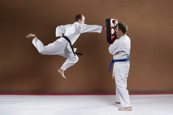 Con un cinturón negro, un deportista entrena un golpe con la mano en un salto en el simulador — Foto de Stock