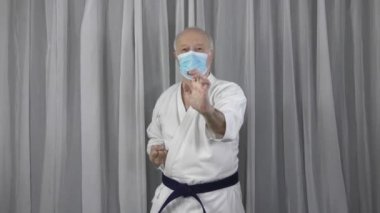 Tıbbi maskeli yaşlı atlet yumrukları yener.