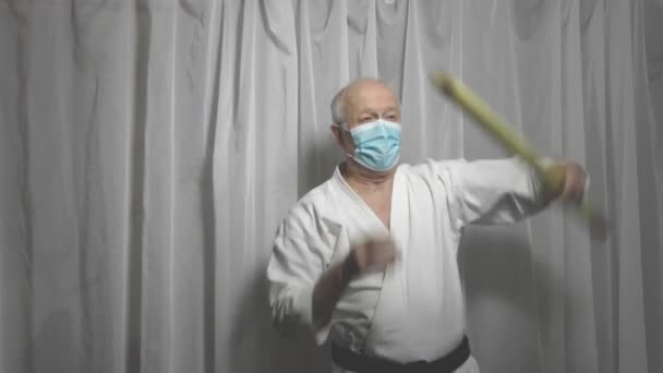 Sportler in medizinischer Maske trainiert Übungen mit dem Stock