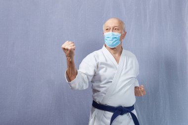 Tıbbi maskeli yaşlı bir erkek sporcunun yaptığı elleri olan bloklar.