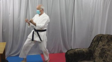 Tıbbi maskeli bir adam tekme atıyor.