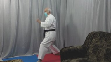 Tıbbi bir maske takan bir sporcu, kendini karantinada bir dizi tekme ve el eğitiyor.