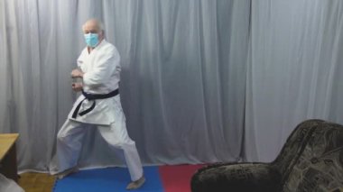 Tıbbi bir maske takan bir sporcu, karantina koşullarında karate eğitimi verir.