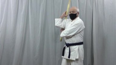 Siyah bir tıbbi maske takan bir sporcu, sopayla karantinaya alınmış teknikleri eğitir.