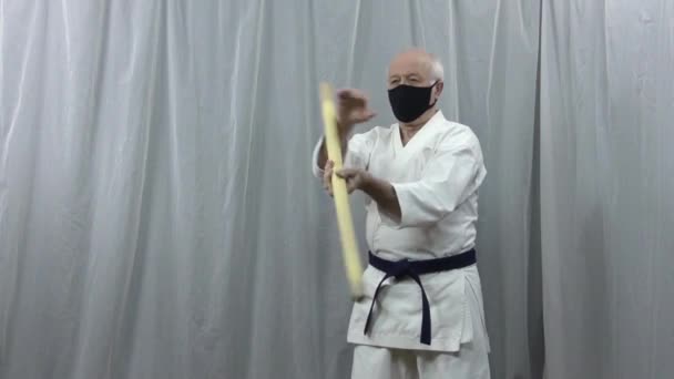 一名运动员戴着医疗面罩 传授在自我隔离条件下使用棍棒的技巧 — 图库视频影像