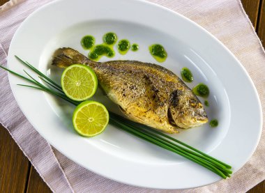 Izgara dorado balığı ve dilimlenmiş limonlu tabak..