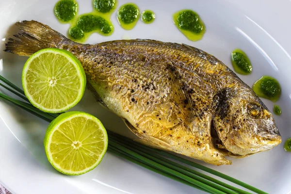 Plate with grilled dorado fish and sliced lime. — Stock Photo, Image