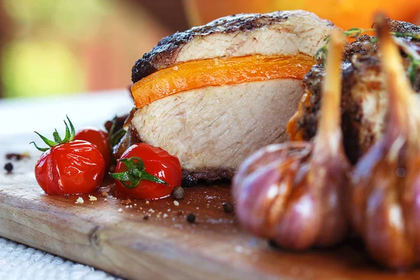 Tahta masaya havuç katılmış taze domuz eti fırınlanmış domates, sarımsak, acı biber ve biberiye. — Stok fotoğraf