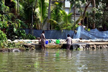 Nehir kıyısında haftalık çamaşırlarını yıkayan iki kadın.