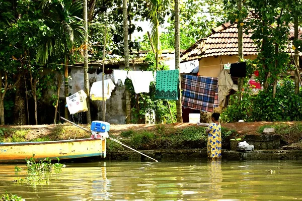 Una anciana lavando su ropa semanal en la orilla del río — Foto de Stock