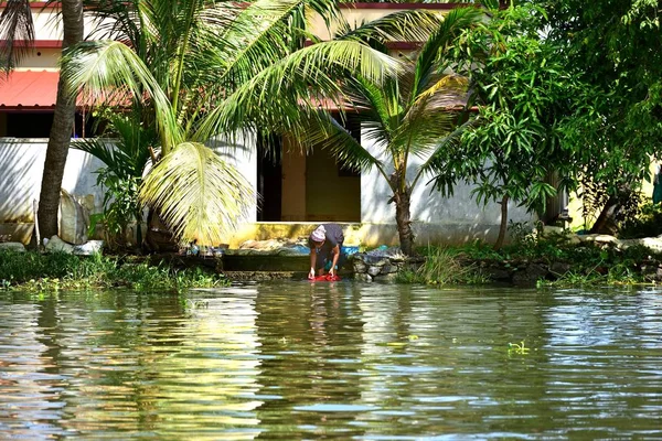 Una anciana lavando su ropa semanal en la orilla del río — Foto de Stock