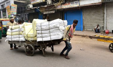 Eski Delhi, Hindistan - 7 Kasım 2019: Aşırı yüklü bir el arabasını yolda taşımak
