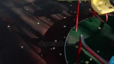 Dolambaçlı atlıkarınca, gölgesiyle boş oyun alanında dönüyor.