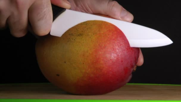 Řezací Mango na černém pozadí, ruce pomalu. — Stock video